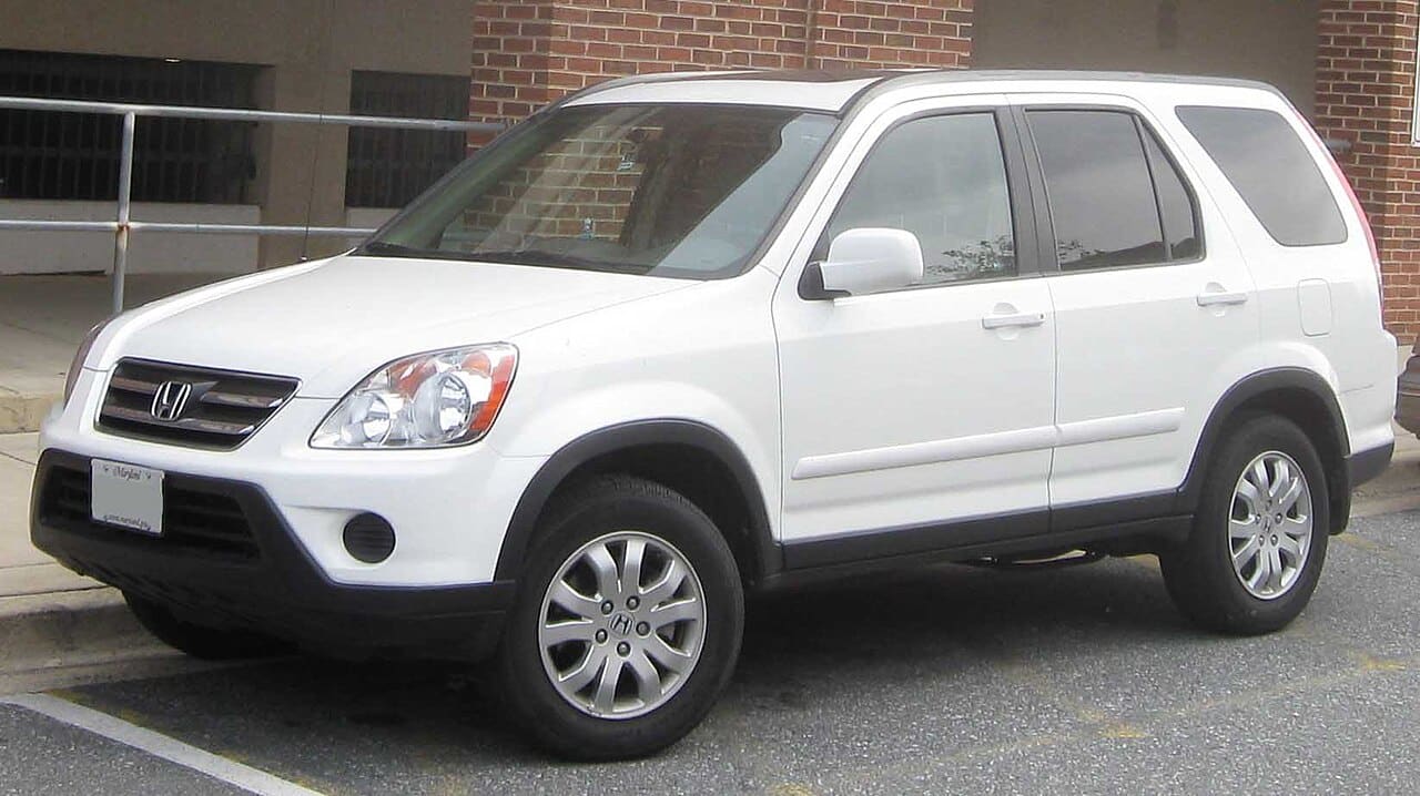White 2005 to 2006 Honda CR-V compact SUV parked near a brick building