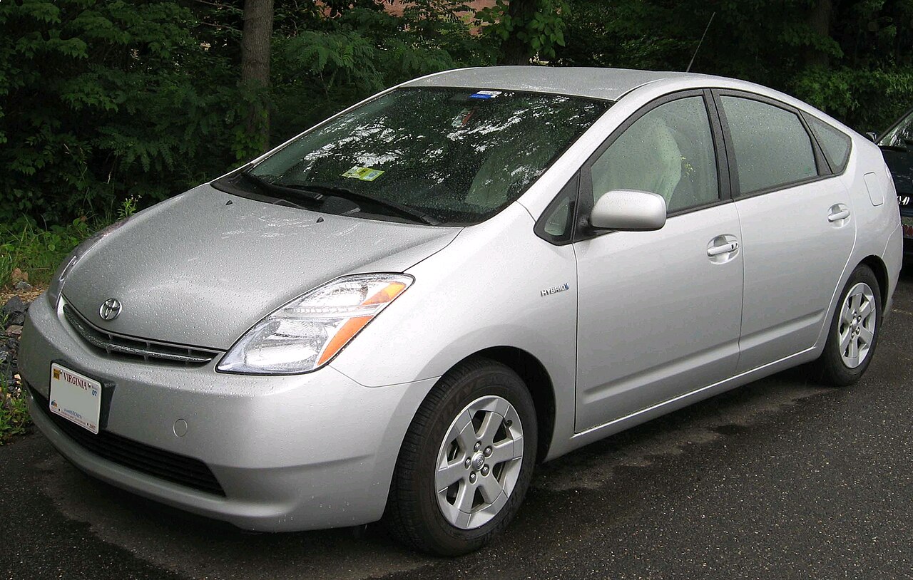 Silver second-generation Toyota Prius hybrid parked beside trees