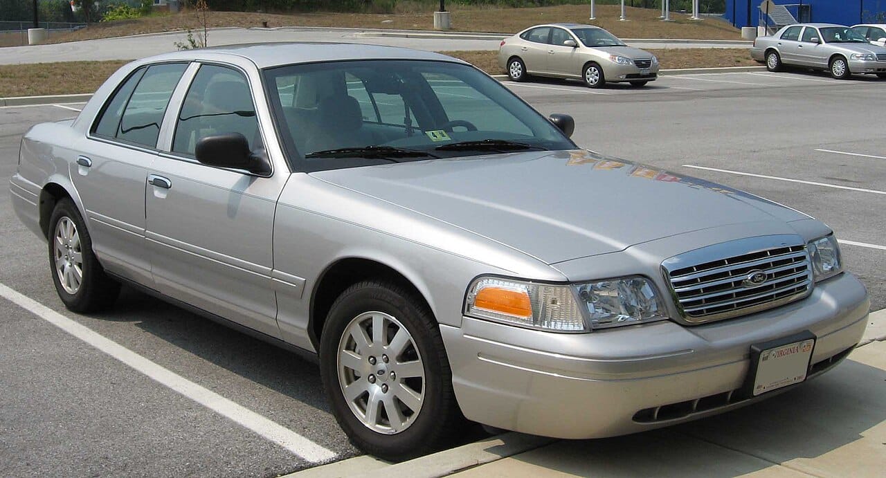 Silver Ford Crown Victoria sedan parked in a large lot
