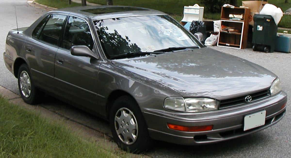 Gray 1990s Toyota Camry sedan parked along a neighborhood street