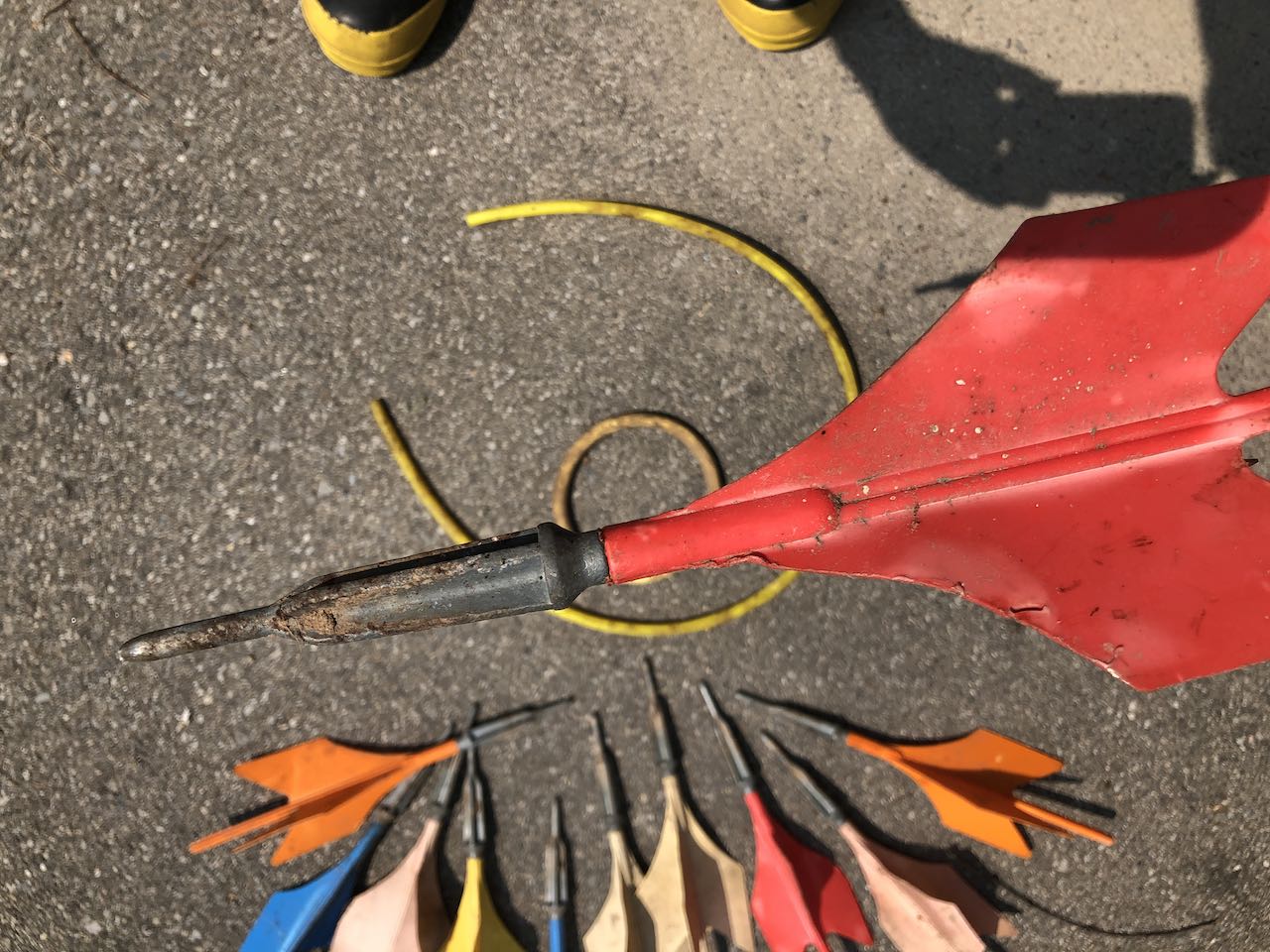 Close-up of a pointed metal lawn dart with red plastic fins