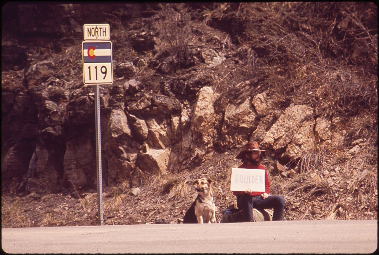 Hitchhiker with a Boulder sign beside Colorado Highway 119
