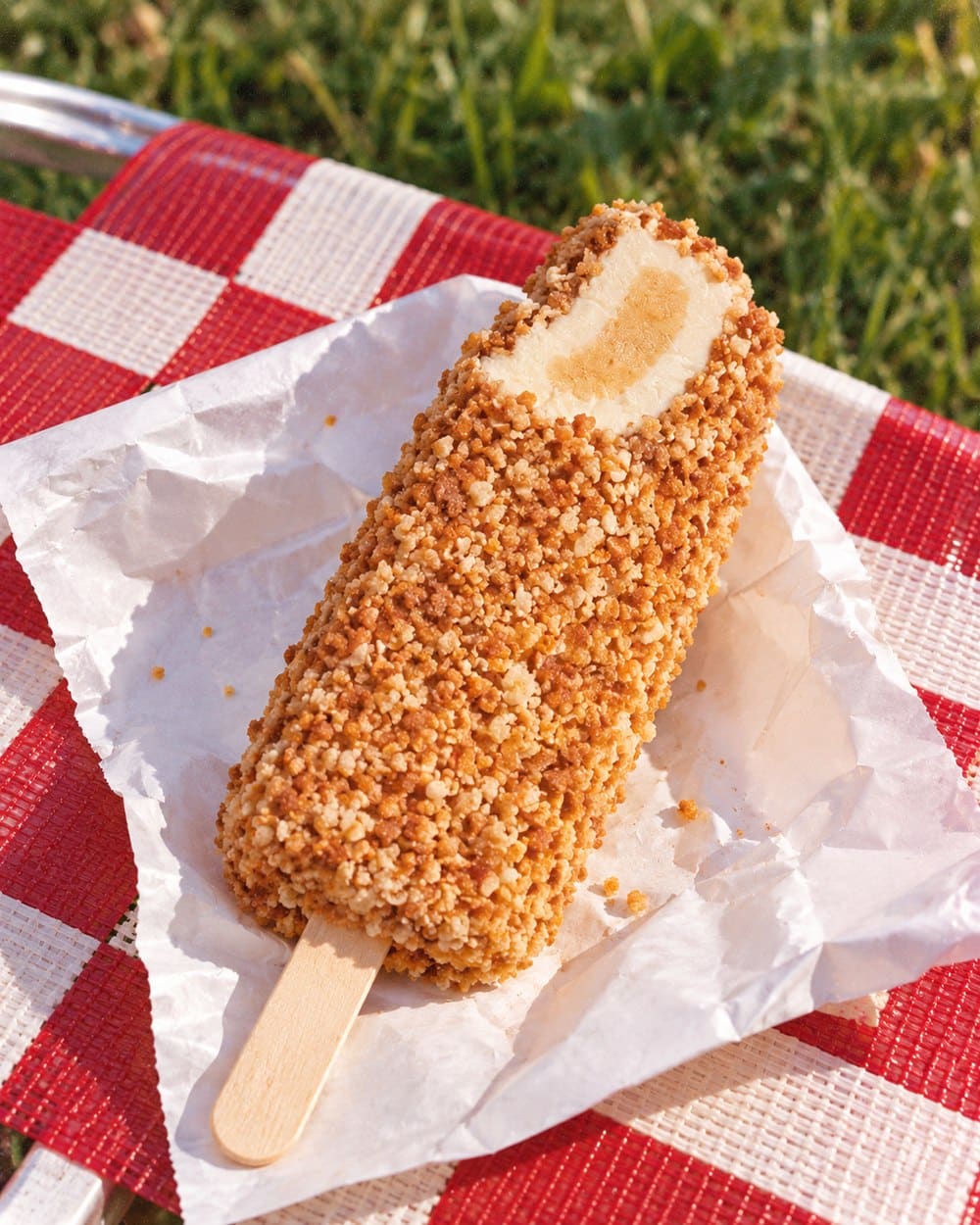 Crumb-coated Toasted Almond ice cream bar with a bite showing the center