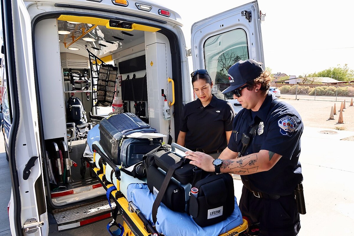 Paramedic shows a Navy corpsman how to prepare equipment at an ambulance