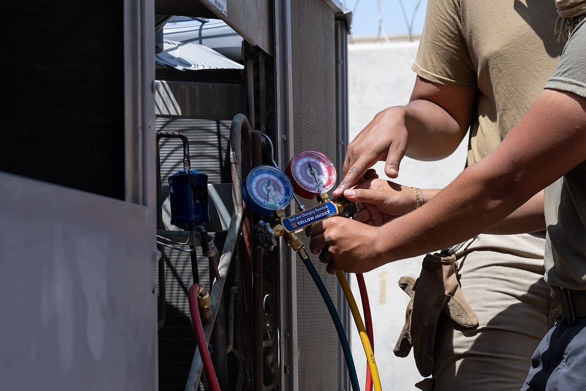 HVAC technicians checking an air conditioner with pressure gauges