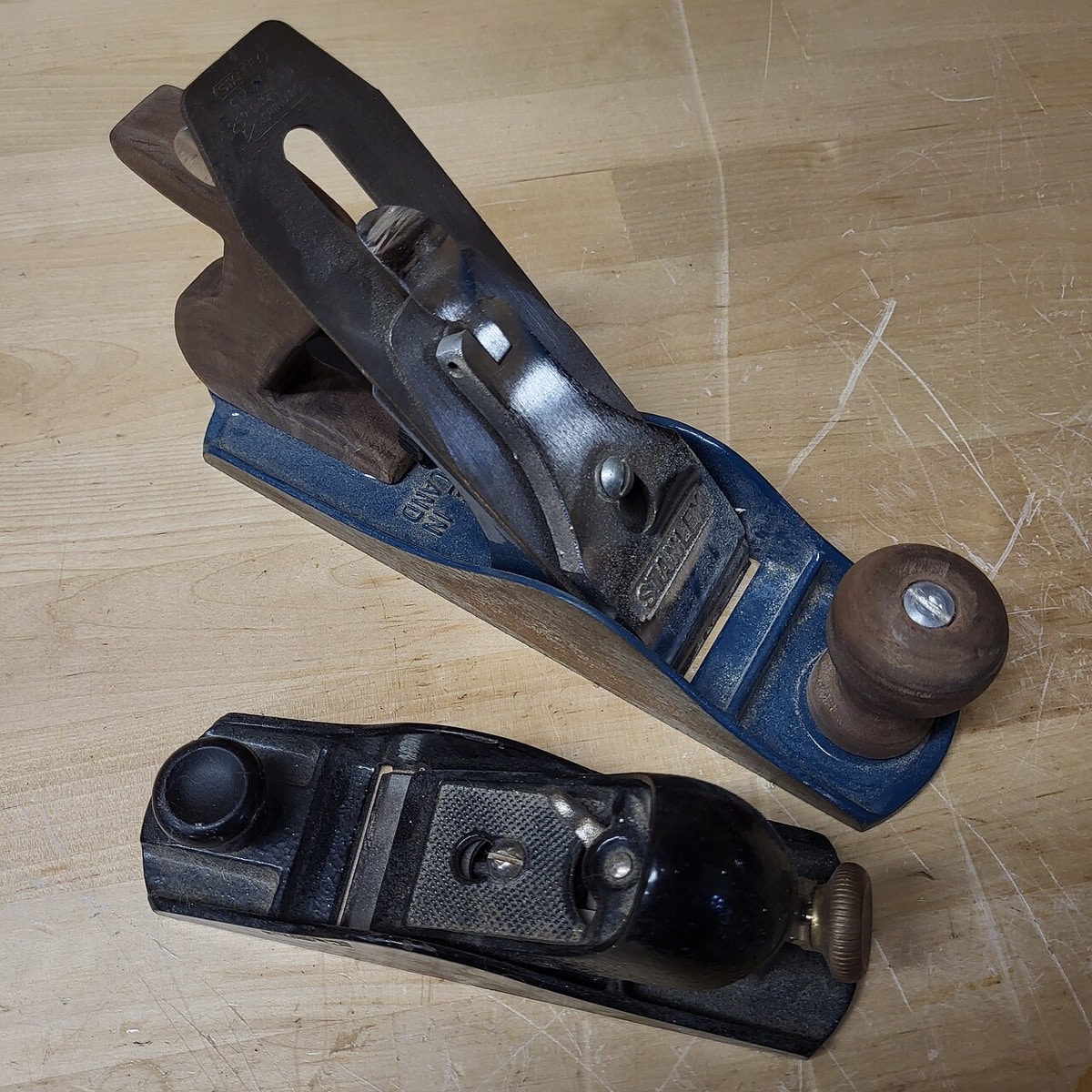 Two iron hand planes with wooden handles on a wooden surface