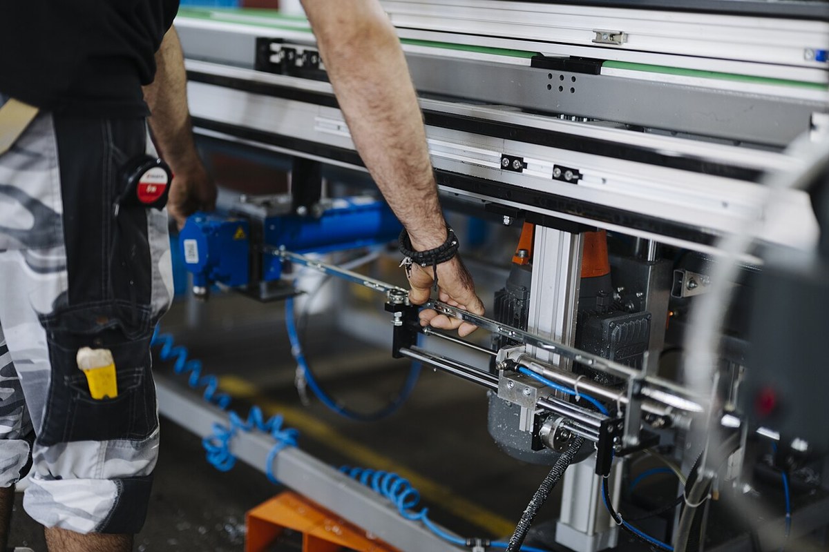 Worker adjusting machinery with a hand tool in a workshop