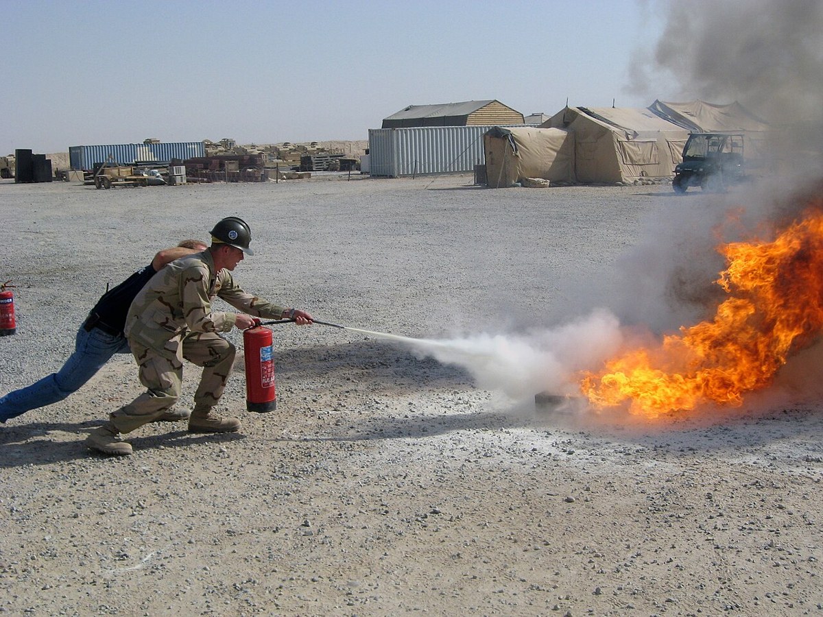 Fire chief instructing a trainee using an extinguisher at Camp Buehring