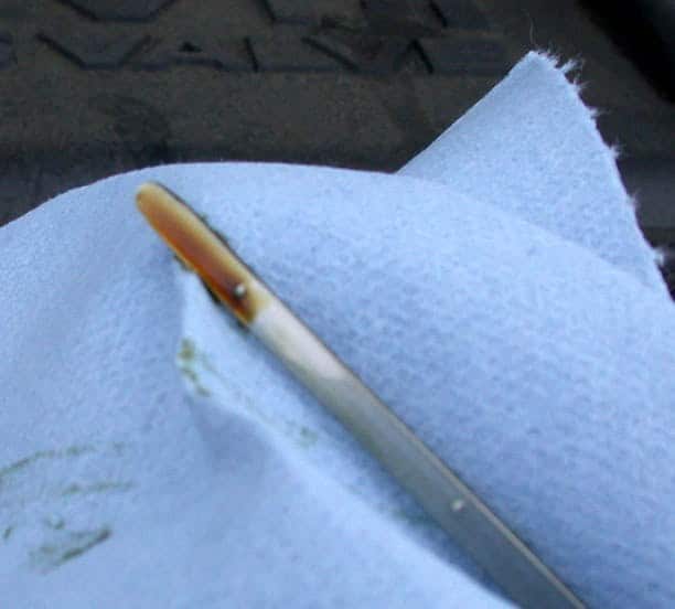 Engine oil visible against the level markings on a dipstick