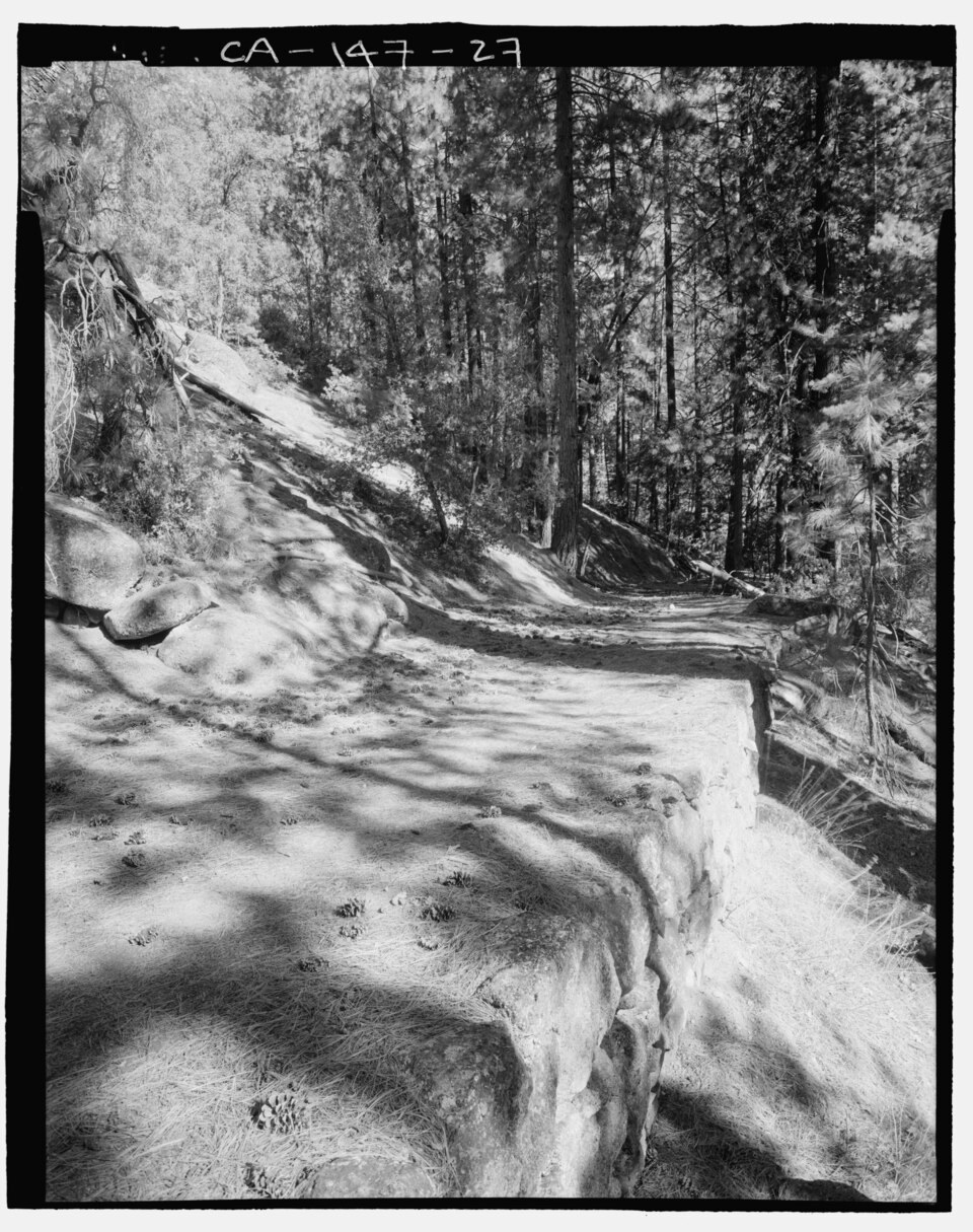 A surviving stretch of Old Big Oak Flat Road, with its stone retaining edge still visible.