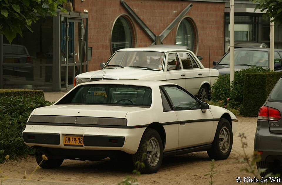 White 1984 Pontiac Fiero viewed from the rear and passenger side
