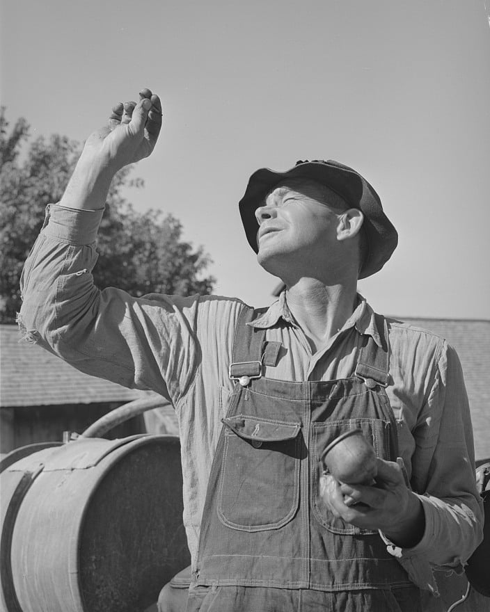 A Utah farmer checking a carburetor jet in August 1940.