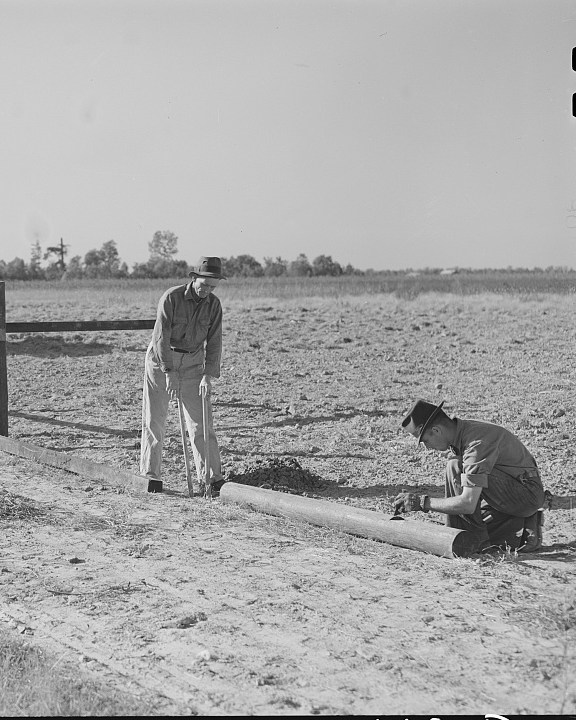 A farmer and his son build a wooden field fence in Mississippi in 1939