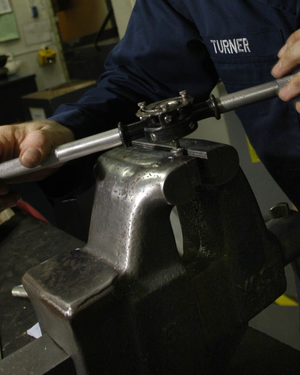 A Navy mechanic turns a die stock to cut threads on a bolt