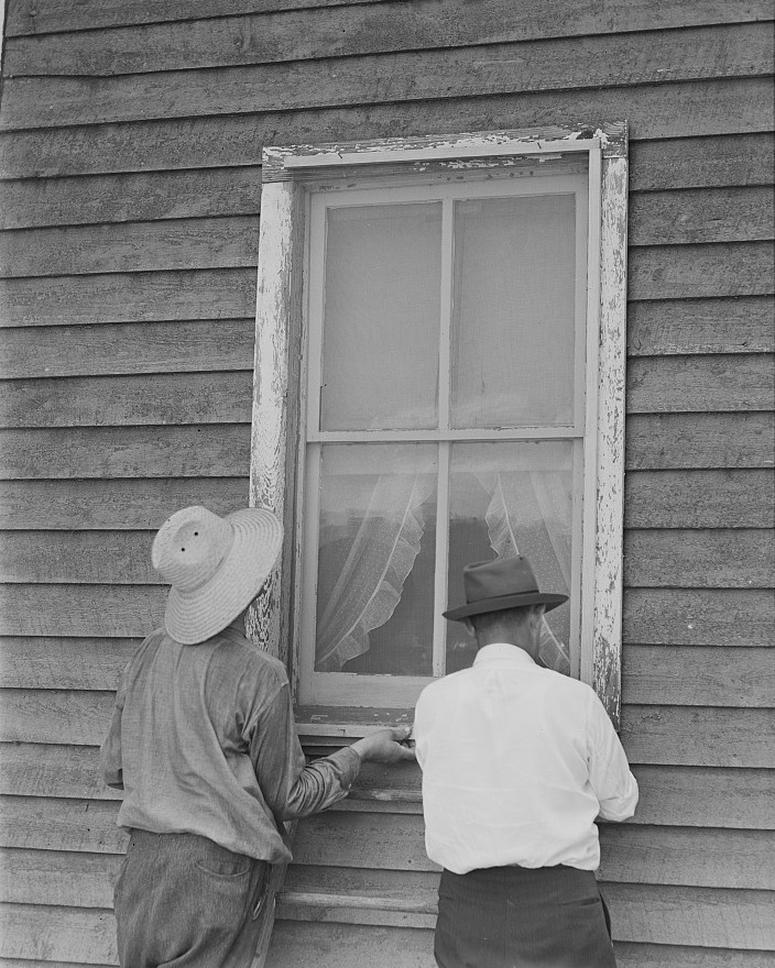 Two men fasten a window screen during a 1941 screening demonstration