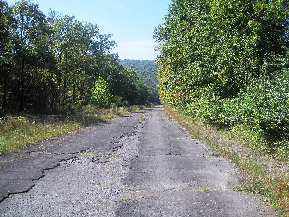 Cracked pavement on the abandoned turnpike: the traffic left, but the old lanes are still legible.